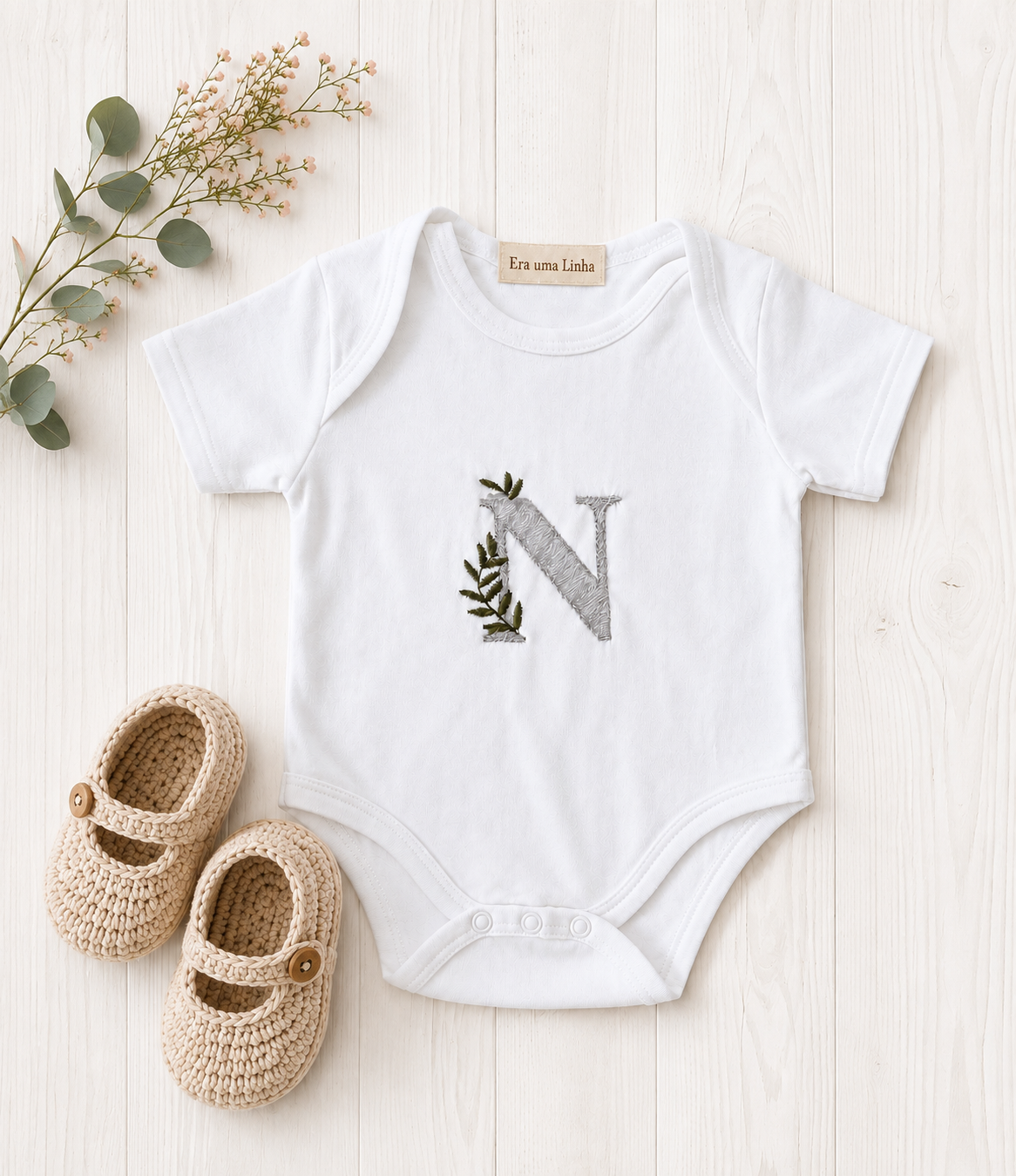 Body branco personalizado com letra N bordada e sapatinhos bege.